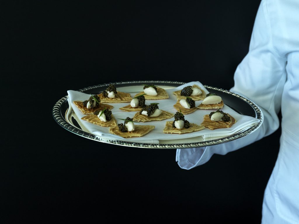 Gloved waiter presenting a silver platter of canapes