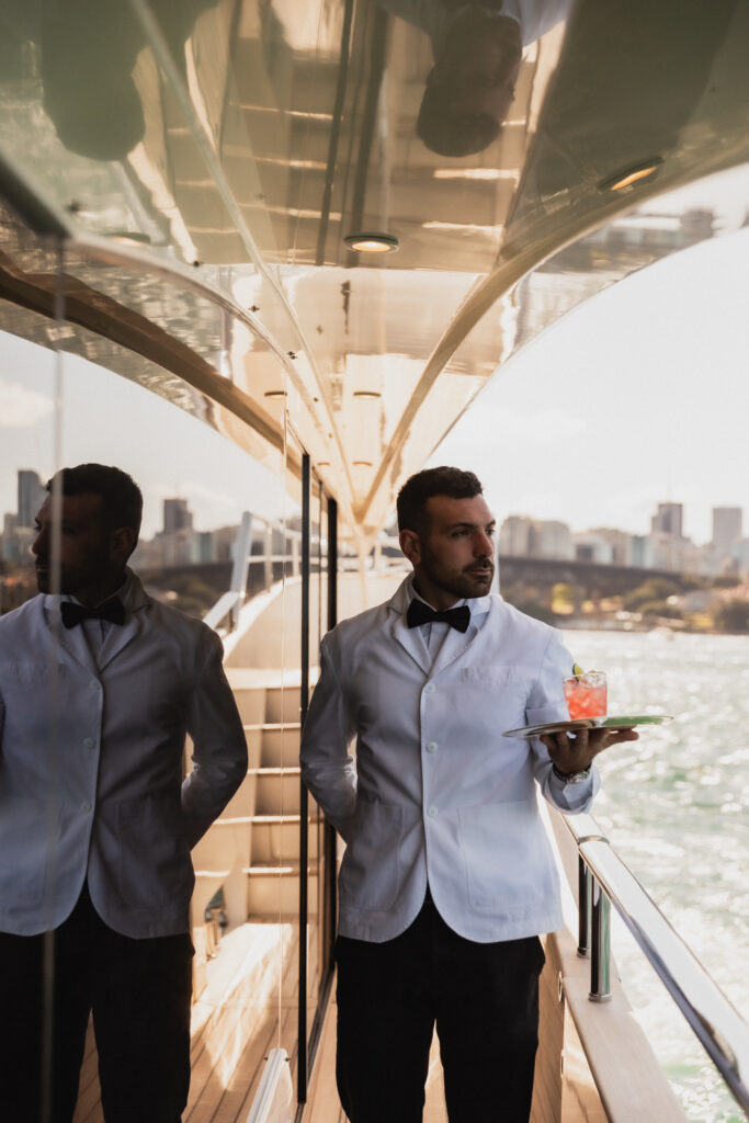 Two guests with drinks aboard a yacht on Sydney Harbour
