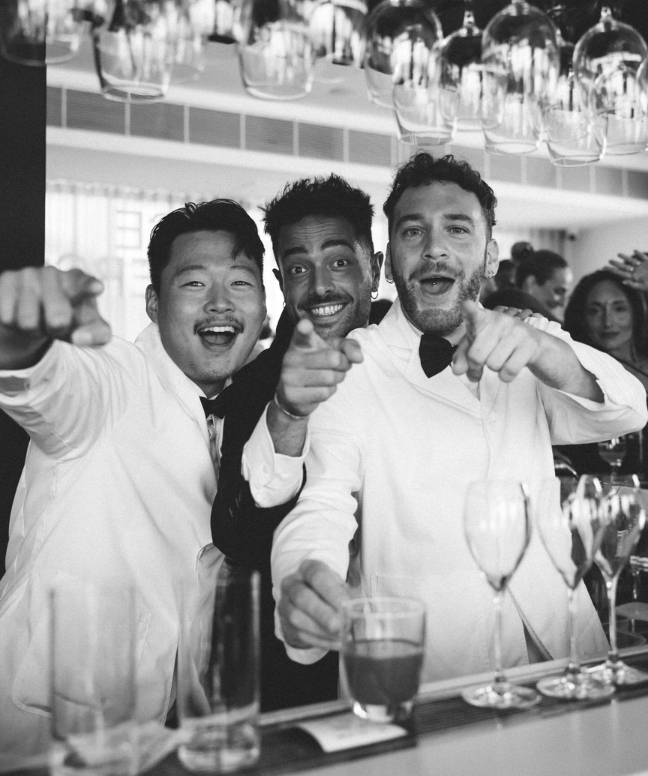 Icebergs bar staff laughing behind the bar, in black and white
