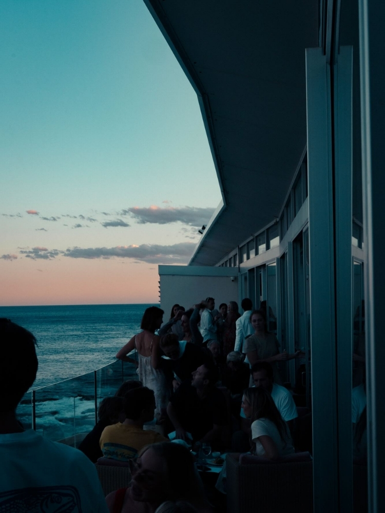 Guests gathered at the Icebergs windows as the sun sets over Bondi