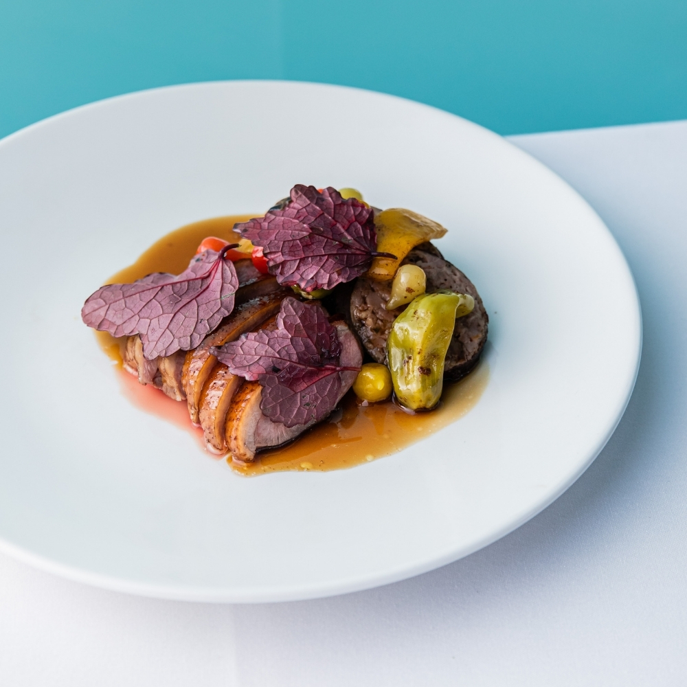 Sliced duck breast with jus on a white plate