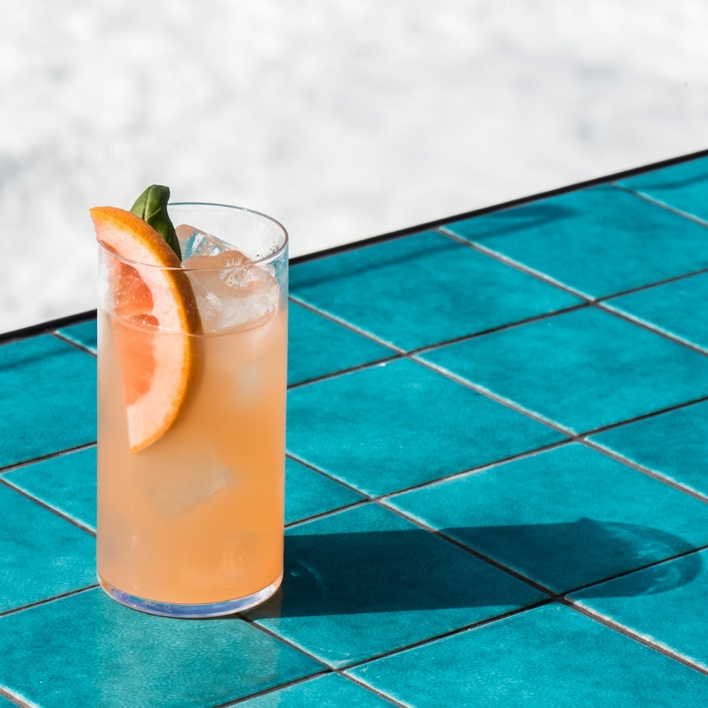 Paloma with a grapefruit slice on a teal tiled table