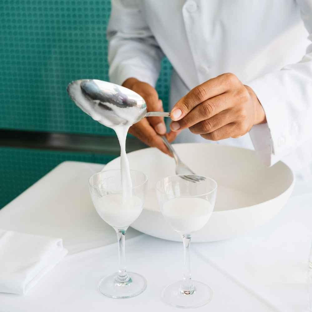 Waiter spooning sgroppino into coupe glasses at the table
